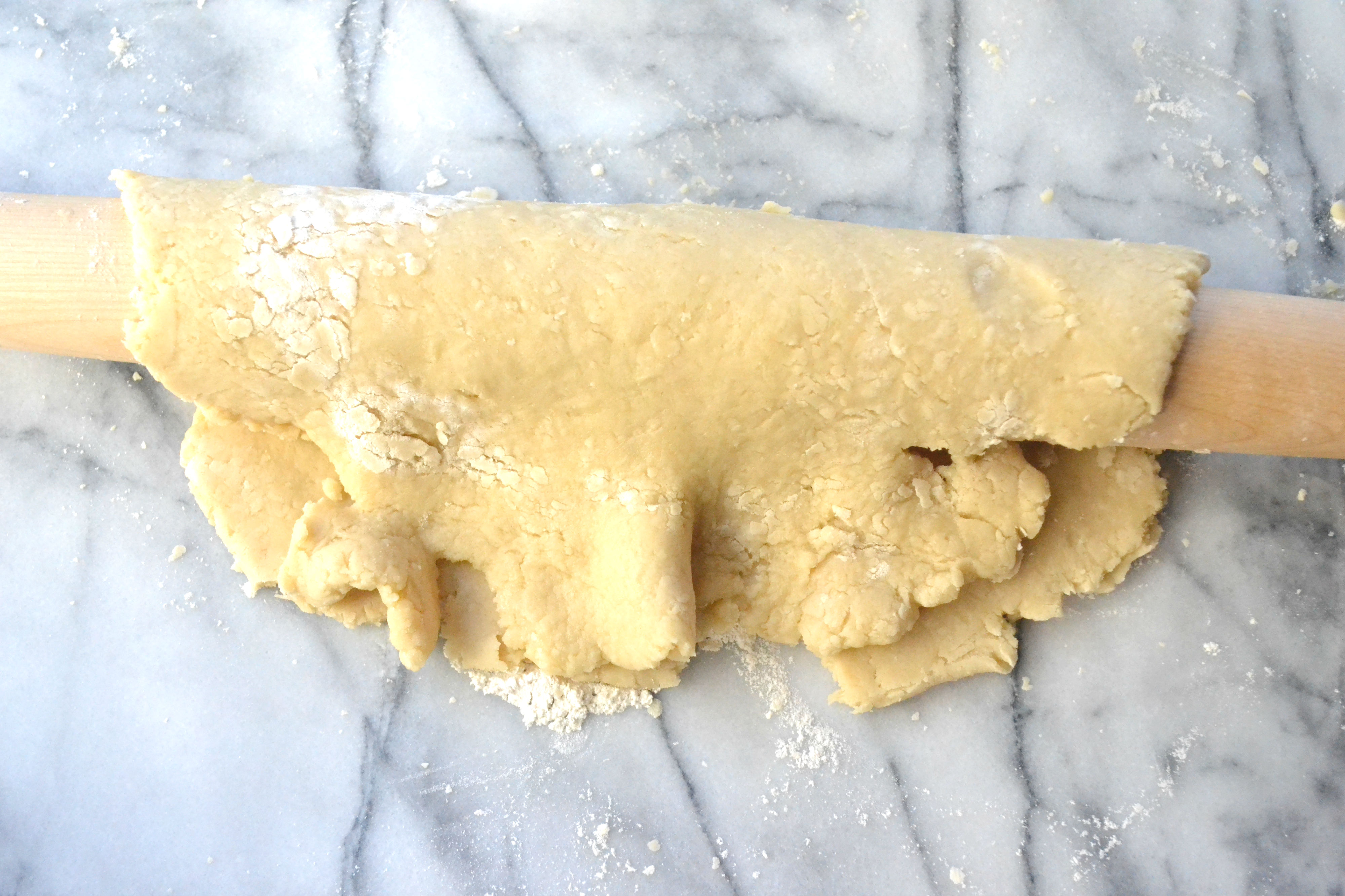 Place the rolling pin in the center of the dough circle. Then carefully lift half of the dough and place on top of the rolling pin, like you're folding the dough in half. 